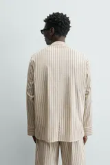 Camisa de calce relajado con diseño de rayas verticales, cuello bowling y manga larga. Cuenta con cierre frontal de botones y tres bolsillos de plastrón: uno en el pecho y dos en la cadera.