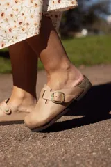 Zueco color tostado con hebilla dorada ajustable, plantilla anatómica y suela de goma.