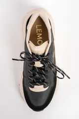 Zapatilla urbana de cuero con diseño de paneles en tonos negro, marrón oscuro y beige. Presenta una suela de plataforma robusta en color beige y cordones jaspeados.