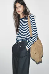 Jersey de punto liso, color azul brillante, con cuello redondo y manga larga. Presenta acabados en rib en puños, cuello y bajo, con aberturas laterales en el ruedo.