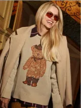 Sweater de punto color marrón claro, con diseño de oso estampado en el frente. Presenta cuello redondo, mangas largas con puños ajustados y corte holgado.