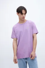 Remera lila de manga corta con estampa fotográfica en la espalda que muestra un paisaje de atardecer sobre el mar.