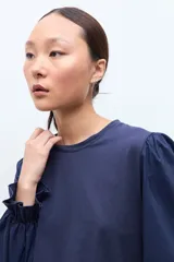 Remera blanca de cuello redondo con mangas largas abullonadas y puños con detalle de volados.