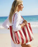 Bolso tipo tote de gran capacidad, confeccionado en tela resistente con diseño de rayas verticales en colores rojo y blanco. Cuenta con asas largas de hombro.
