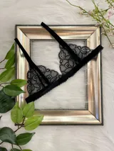 Bralette negro de encaje con breteles finos regulables y cierre trasero con gancho.