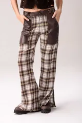Pantalón de tiro medio con diseño de cuadros tartán en tonos marrón, blanco y negro, combinado con detalles de cuero en la parte superior y grandes bolsillos frontales.