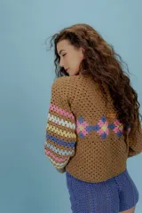 Saco de crochet color marrón con diseño de patchwork con motivos florales en tonos rosa, celeste y amarillo. Tiene cuello camisero, cierre frontal con botones y mangas largas. Tejido en algodón.