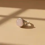 Anillo de plata 925 con piedra de cuarzo rosa natural en corte cabujón y banda con diseño trenzado.