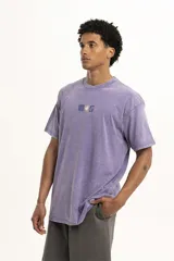 Remera de corte oversize y estilo vintage con efecto lavado, color violeta, con cuello redondo y estampa pequeña central con motivos florales y geométricos.