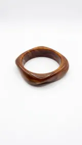 Pulsera rígida de acrílico con diseño asimétrico y efecto carey en tonos marrones.