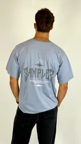 Remera de manga corta color azul grisáceo, con cuello redondo y estampa gráfica en el pecho.