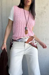 Chaleco tejido de punto color rosa con diseño de trenzas.
