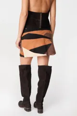 Mini falda tipo cruzada confeccionada en cuero, con detalle de cintura con tachas metálicas.