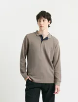 Remera de punto canalé francés con cuello polo, manga larga y abotonadura frontal con botones de madera. Presenta una cartera a contratono y medialuna interior.