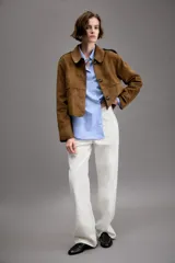Chaqueta corta de efecto ante en color marrón, con cuello solapa, manga larga y trabillas en los hombros. Presenta cierre frontal con botones y bolsillos delanteros de doble vivo.