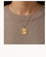 Collar de bronce dorado con cadena fina y dije circular texturizado en forma de sol con una circona en el centro.