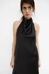 Vestido largo de satén con cuello halter y escote fluido. Presenta un diseño de espalda descubierta con cierre de cremallera oculta y lazada ajustable en el cuello.