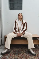 Campera con capucha, de tela tipo peluche a rayas verticales color marrón y blanco, con ribete color beige.