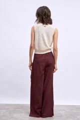 Chaleco de punto color marrón, con escote en V y cierre frontal con botones dorados.