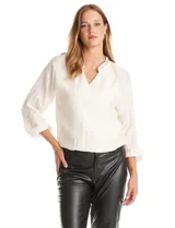 Blusa de satén color blanco, con cuello a la base decorado con mostacillas bordadas y escote en V. Presenta mangas largas con puños elásticos y ruedo elastizado.