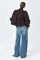Jean de cinco bolsillos en denim de algodón rígido, con piernas maxivolumen de diseño curvo y corte estándar de cadera a muslo, ligeramente ceñidas en el bajo mediante trabilla. Cuenta con cintura de tiro alto, cierre y botón.