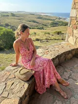 Vestido largo color magenta con cuello halter y estampado caleidoscópico en tonos rosados y crudos, diseño de falda en capas.