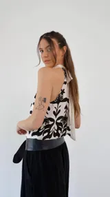 Top de seda color crema con estampado de flores negras, cuello halter y lazo en la espalda.