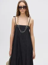 Vestido midi de denim color marrón, con corte holgado, breteles finos con lazos ajustables y detalle de volado en el ruedo.