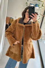 Campera reversible de cuero genuino napalán, color marrón tostado, con interior de corderito sintético, bolsillos frontales aplicados, cuello amplio y cierre frontal de cremallera metálica.
