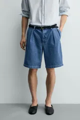 Bermuda de denim de algodón con corte relaxed fit, cintura con pliegues dobles en el delantero, bolsillos laterales y traseros de doble vivo, con efecto lavado y cierre frontal con cremallera y botón.