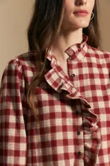 Camisa de algodón a cuadros con diseño de volados frontales, cuello alto y mangas largas con leve volumen.