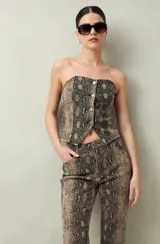 Top strapless con estampado animal print de serpiente en tonos beige y negro, calce al cuerpo, frente con botones metálicos y ruedo en punta.