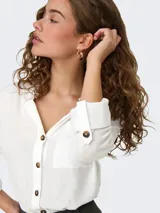 Camisa de viscosa sostenible de manga larga con opción de enrollado, escote en V con cuello camisero, cierre frontal de botones y un bolsillo aplicado en el pecho.
