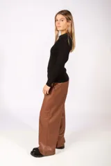 Pantalón de corte recto y tiro alto confeccionado en simil cuero color marrón, con bolsillos laterales y cierre frontal.