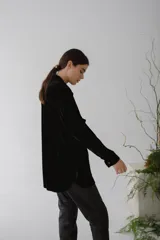 Camisa color marrón anaranjado de terciopelo, con cuello clásico, cierre frontal con botones, dos bolsillos de parche en el pecho y mangas largas con puños abotonados.