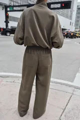 Pantalón de tiro alto con pernera recta, cintura elástica en la parte posterior y nervio marcado en el frente. Cuenta con cierre frontal de botón y ganchos, bolsillos delanteros y bolsillos de plastrón en la parte trasera.