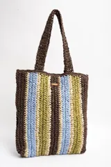 Bolso tipo shopper tejido de papel con diseño de rayas verticales en tonos marrón, celeste, verde oliva y beige. Cuenta con doble asa de hombro y detalle de etiqueta de marca en el frente.