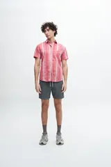 Camisa manga corta a rayas verticales rojas y grises, confeccionada en tela 100% algodón. Tiene bolsillo en el pecho, botones personalizados y calce clásico.