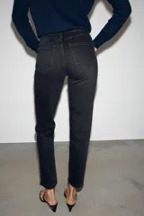 Jeans mom fit de tiro alto color negro con efecto lavado, diseño de cinco bolsillos y corte tobillero.