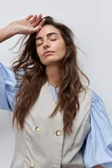 Chaleco de calce entallado color beige, de estilo cruzado con doble botonadura y escote redondo.