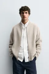 Chaqueta tipo bomber de punto en hilatura de lana, con cuello subido, manga larga, bolsillos de vivo en la cadera, acabados en rib y cierre frontal de cremallera.