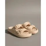 Sandalias chancletas de goma color beige con diseño texturizado en la suela, doble tira ajustable con hebillas y estilo slip-on.