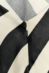 Vestido midi de satén con diseño a rayas diagonales en color negro y blanco crudo, escote halter con tirantes finos para anudar al cuello y espalda descubierta.
