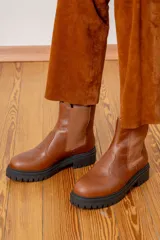 Bota tipo chelsea de cuero color chocolate con acabado brillante, paneles laterales elásticos y suela track negra de goma.
