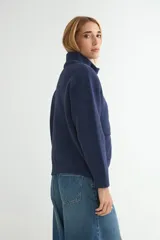 Abrigo de punto negro con cuello alto y cierre frontal completo. Presenta un diseño de corte recto con bolsillos frontales y terminaciones en tejido acanalado.