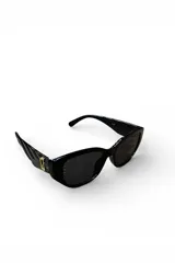 Lentes de sol Aurum con armazón negro de diseño anguloso, lentes oscuras y detalles dorados en las patillas.
