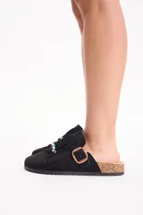 Zueco negro de gamuza con flecos frontales decorados con cuentas de colores y tira con hebilla ajustable lateral.