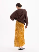 Pollera midi de corte al bies confeccionada en terciopelo con acabado brillante y textura arrugada.