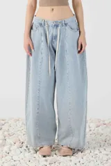 Jean baggy de tiro bajo y pierna amplia, confeccionado en denim con efecto lavado. Presenta costuras curvas frontales, cinco bolsillos, trabillas para cinturón y cordón ajustable en la cintura.