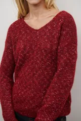 Buzo de punto color gris claro con motas oscuras, escote en V y mangas largas.